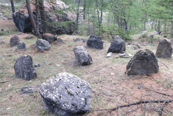 Un cromlech con un menhir posizionato al centro. Sullo sfondo: il masso che segna il tramonto del sole al solstizio d’estate